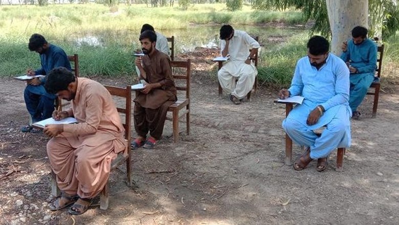 Larkana University students solve papers under scorching sun
